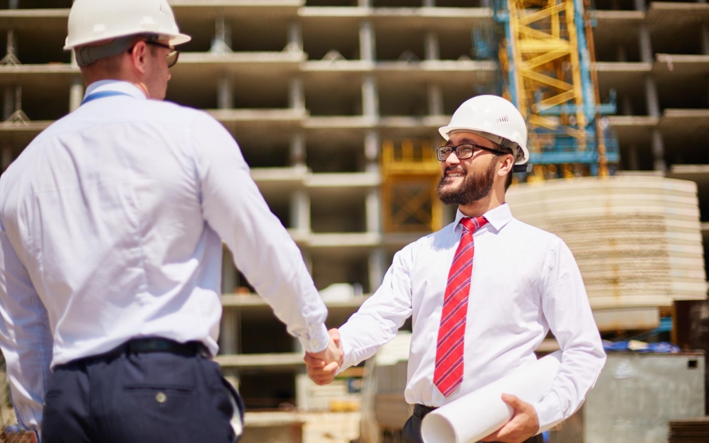 Image of two people on a construction site shaking hands.