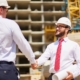 Image of two people on a construction site shaking hands.